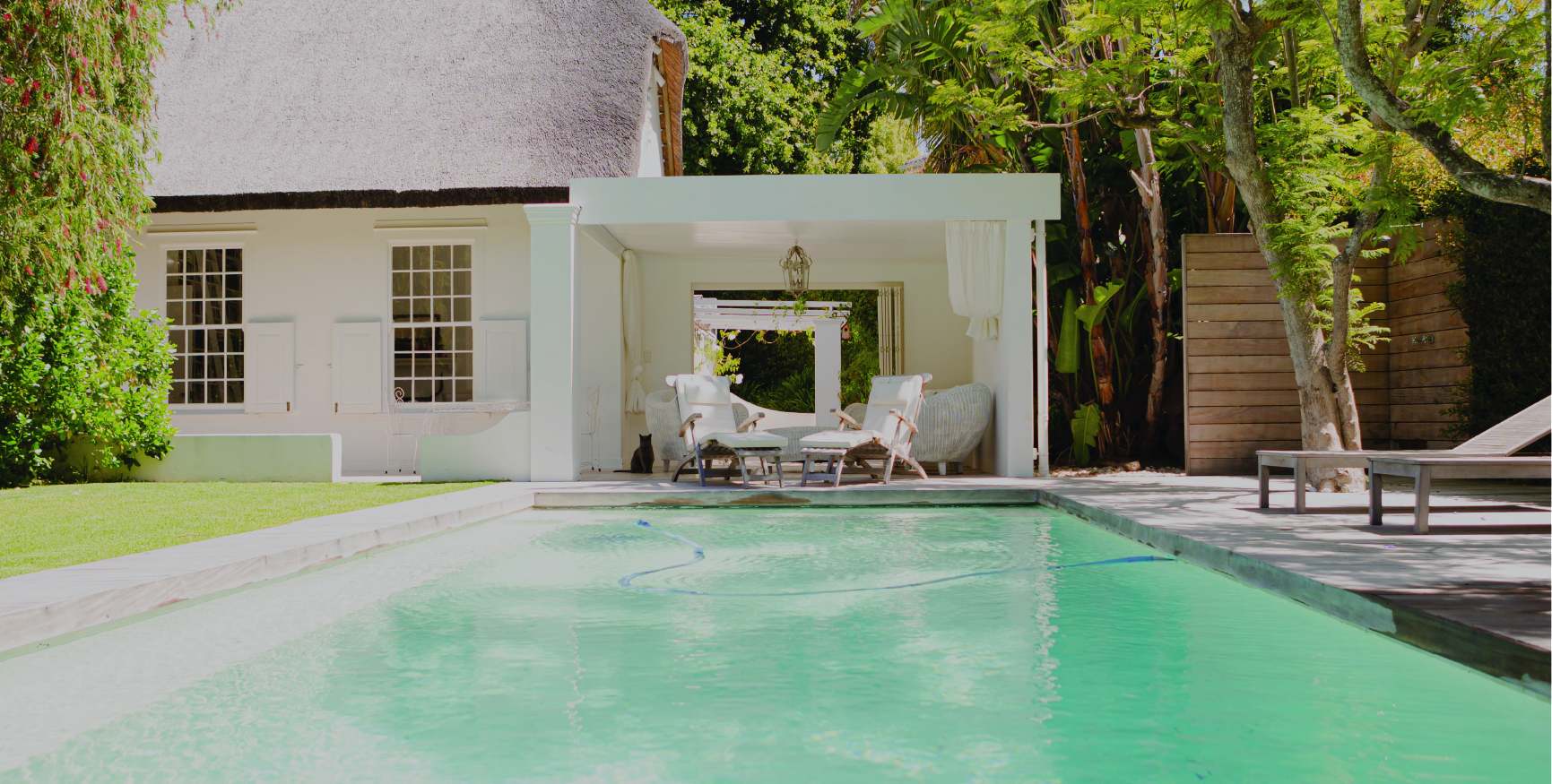 A beautiful backyard with a zen pool and large white home behind it.